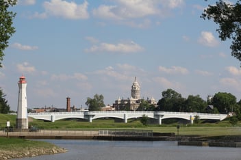 Landscape image of downtown Troy, Ohio with the Adams Bridge and the Capital building behind it, in a sky full of clouds